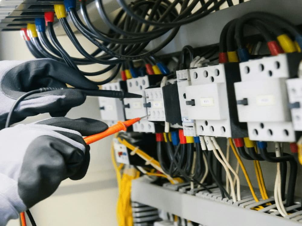 Električar z merilnikom preverja ožičenje v elektro omarici